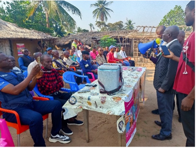 Polio Awareness Event in DRC A local event to raise awareness about polio vaccination, with speakers addressing the audience using a megaphone while healthcare supplies are displayed on the table.