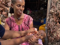 Mother and Child Receiving Polio Vaccine in Ethiopia A mother smiles as her baby is vaccinated against polio in Ethiopia, showcasing local efforts to combat the disease.