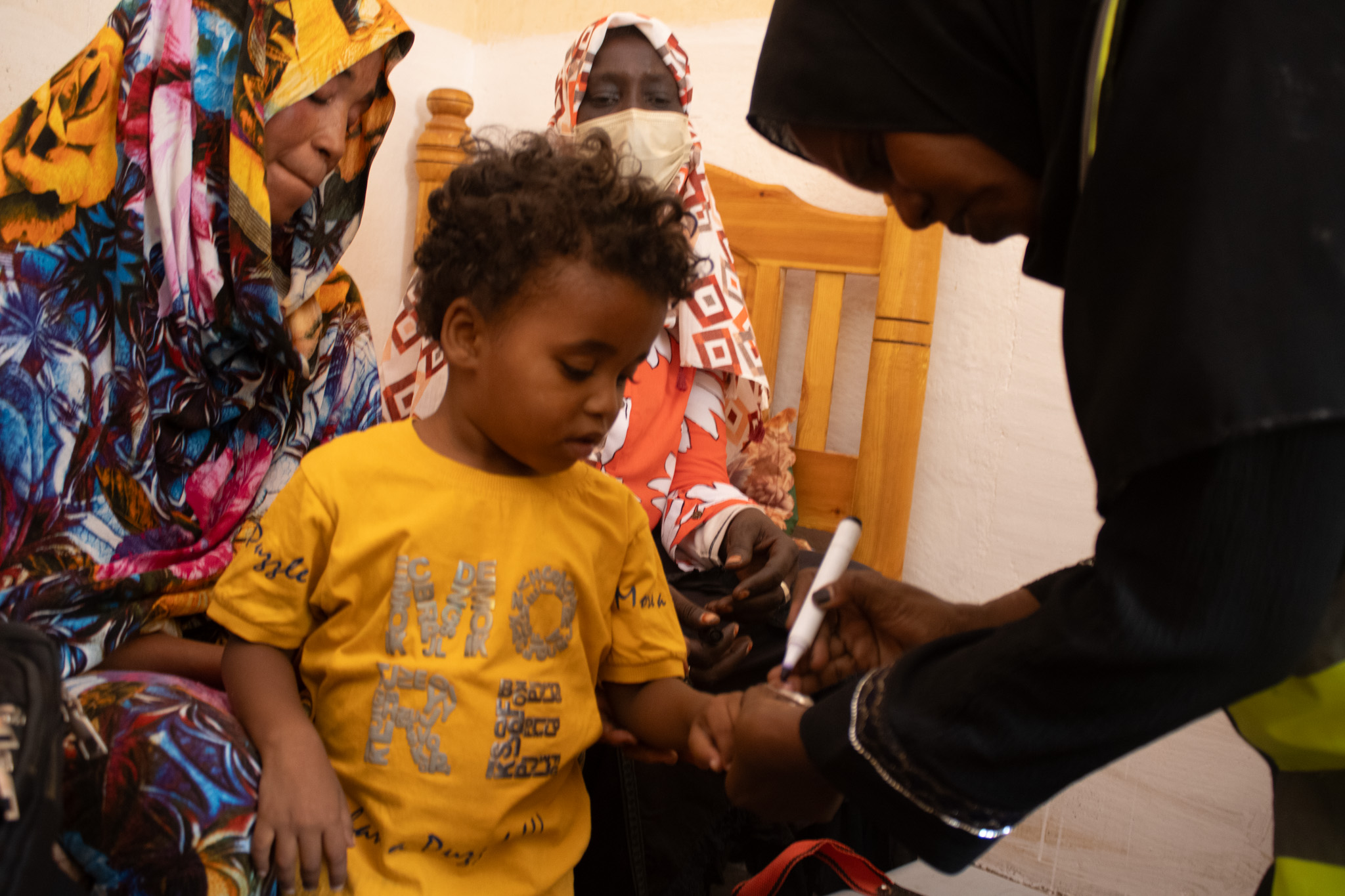 Health Worker Marks Vaccinated Child A healthcare worker marks the finger of a child after administering a vaccine, signifying the completion of a successful vaccination.