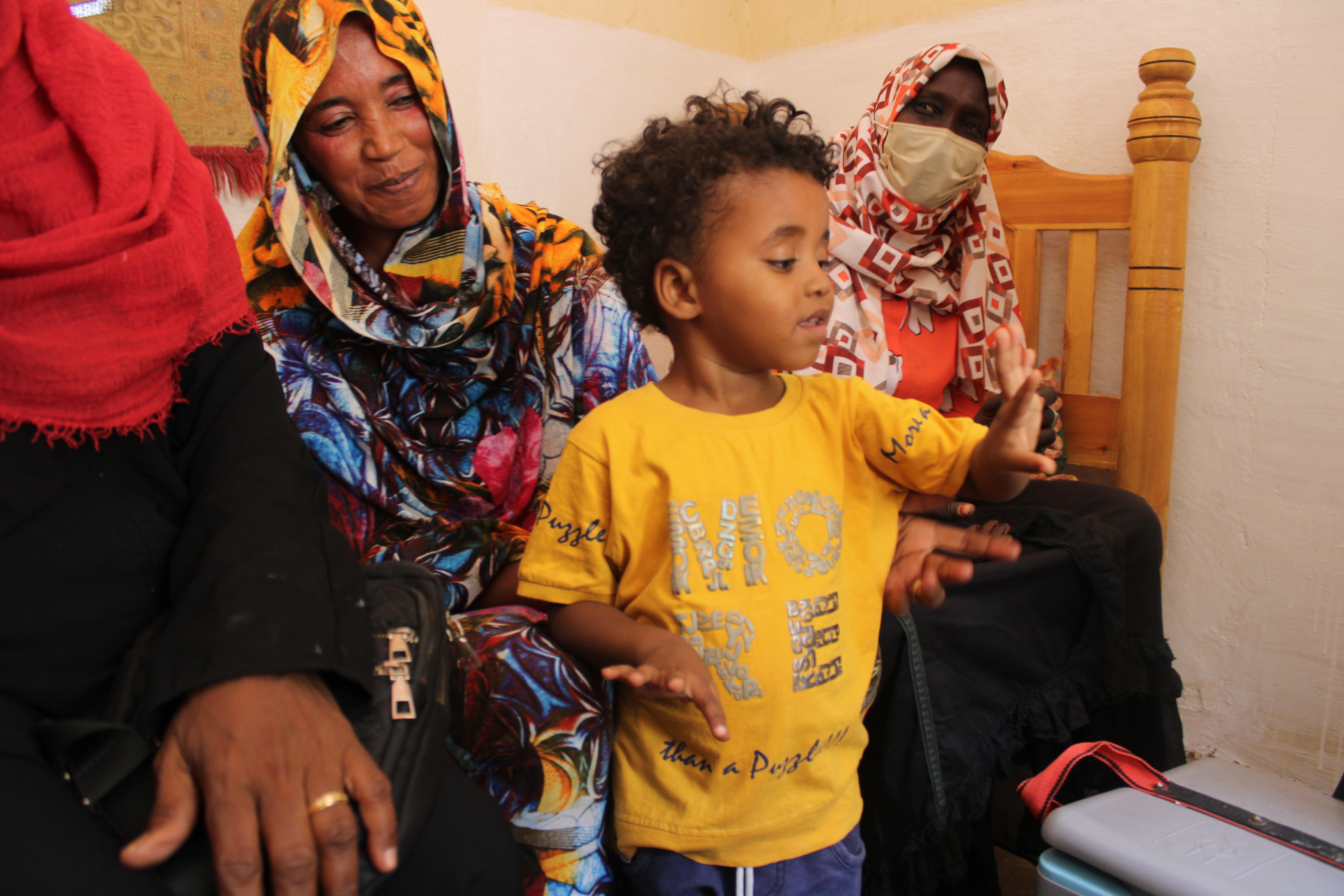 Child Proudly Displays Vaccinated Finger A young child proudly shows his finger after receiving a vaccination, surrounded by family members who smile in support. The moment highlights the child’s participation in the vaccination process and the positive involvement of his family in promoting health and well-being.