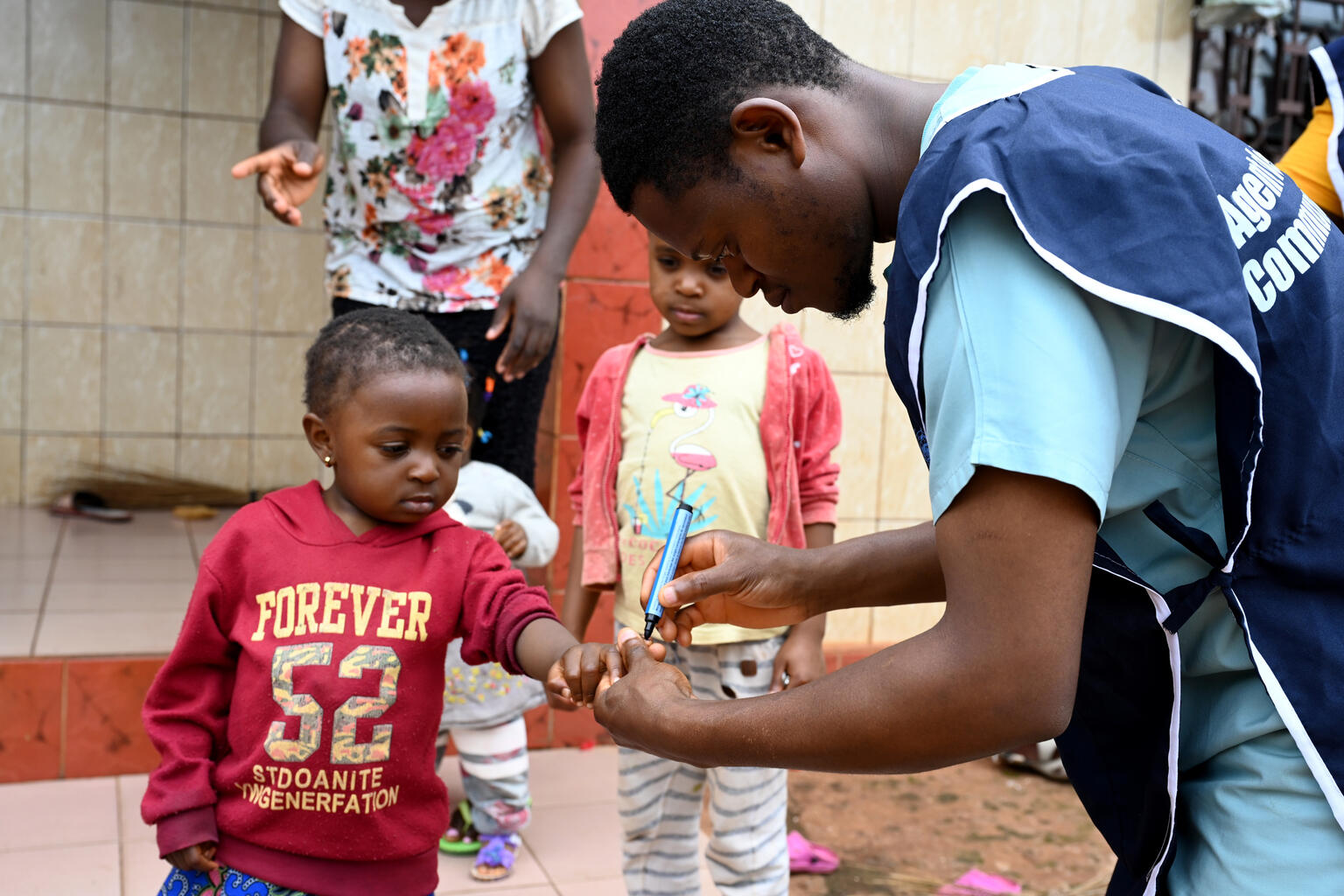 A health worker marking a child's finger with ink as part of the vaccination process.