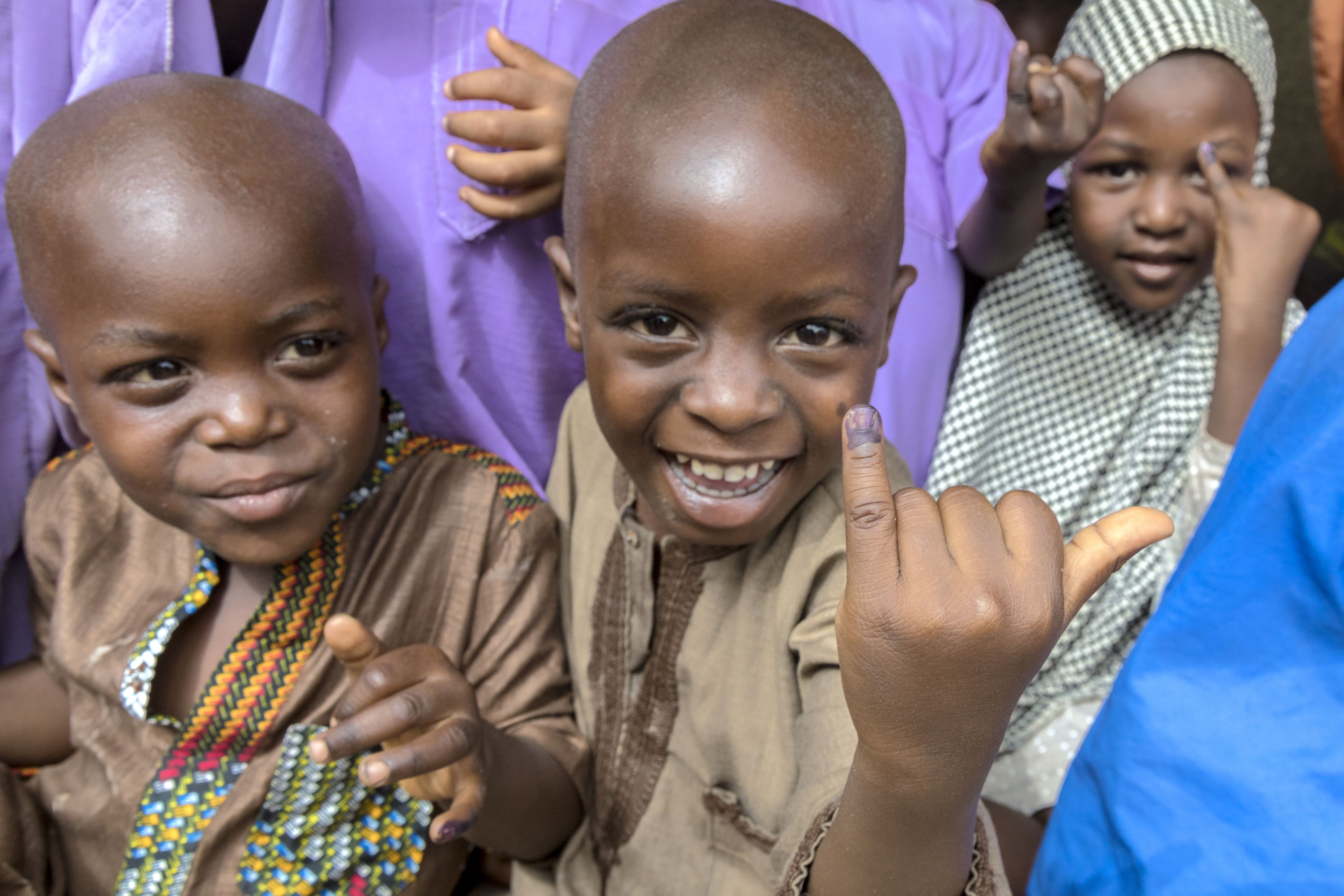 Children showing their pinky as a sign that they got the vaccine