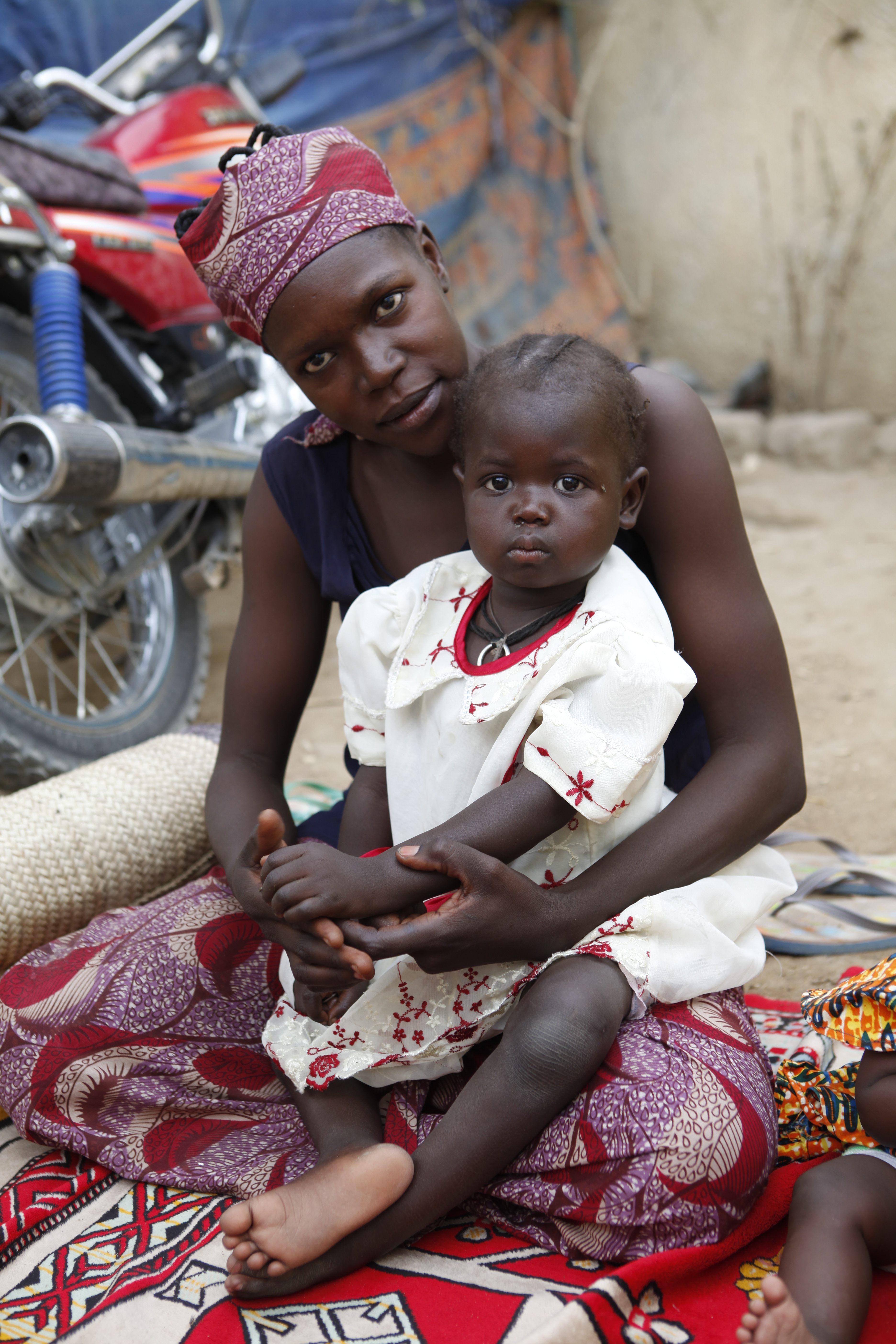 A mother holding her baby sitting on the floor looking at the picture