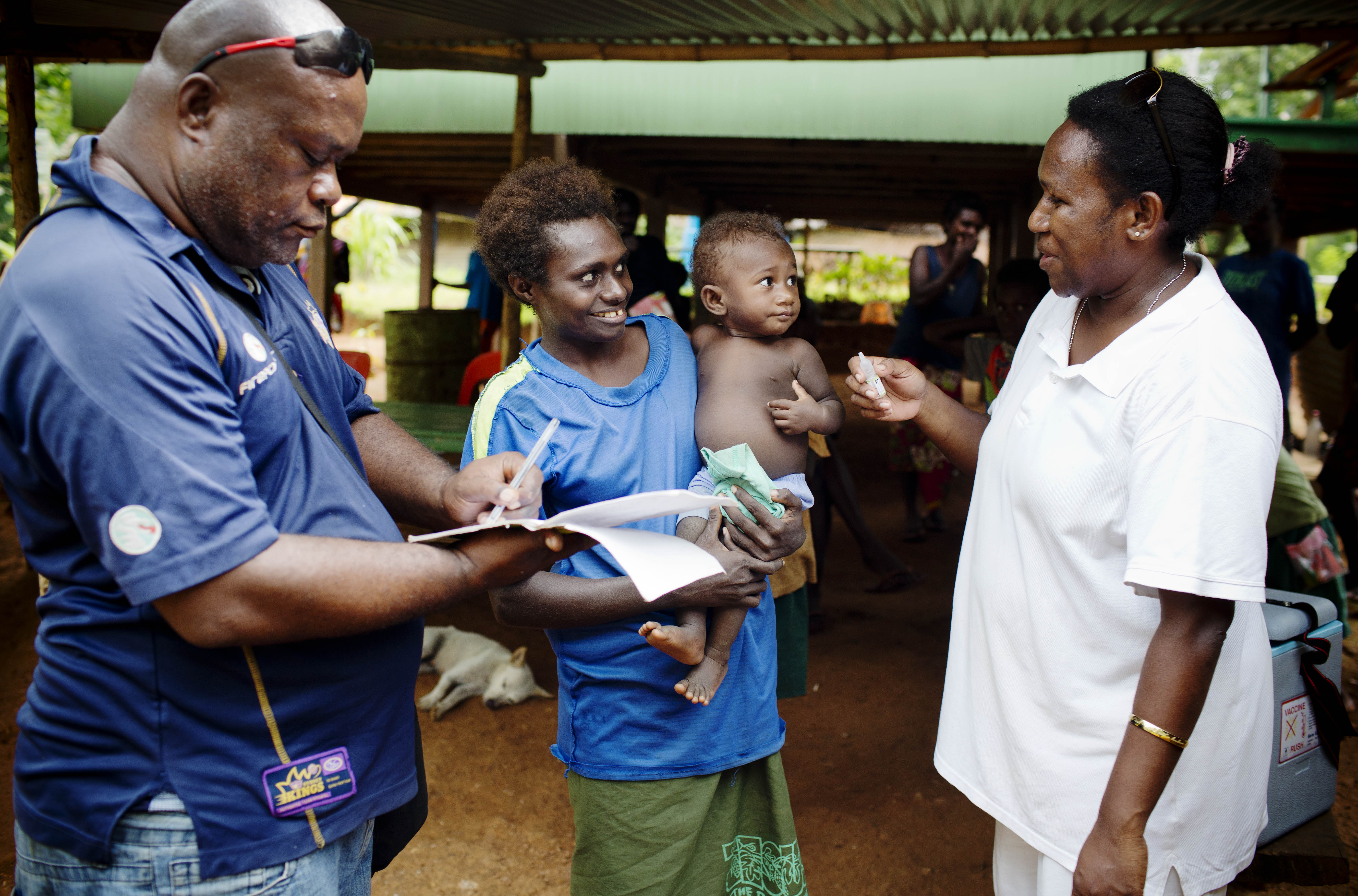 Woman holding her baby and talking to two Unicef representatives