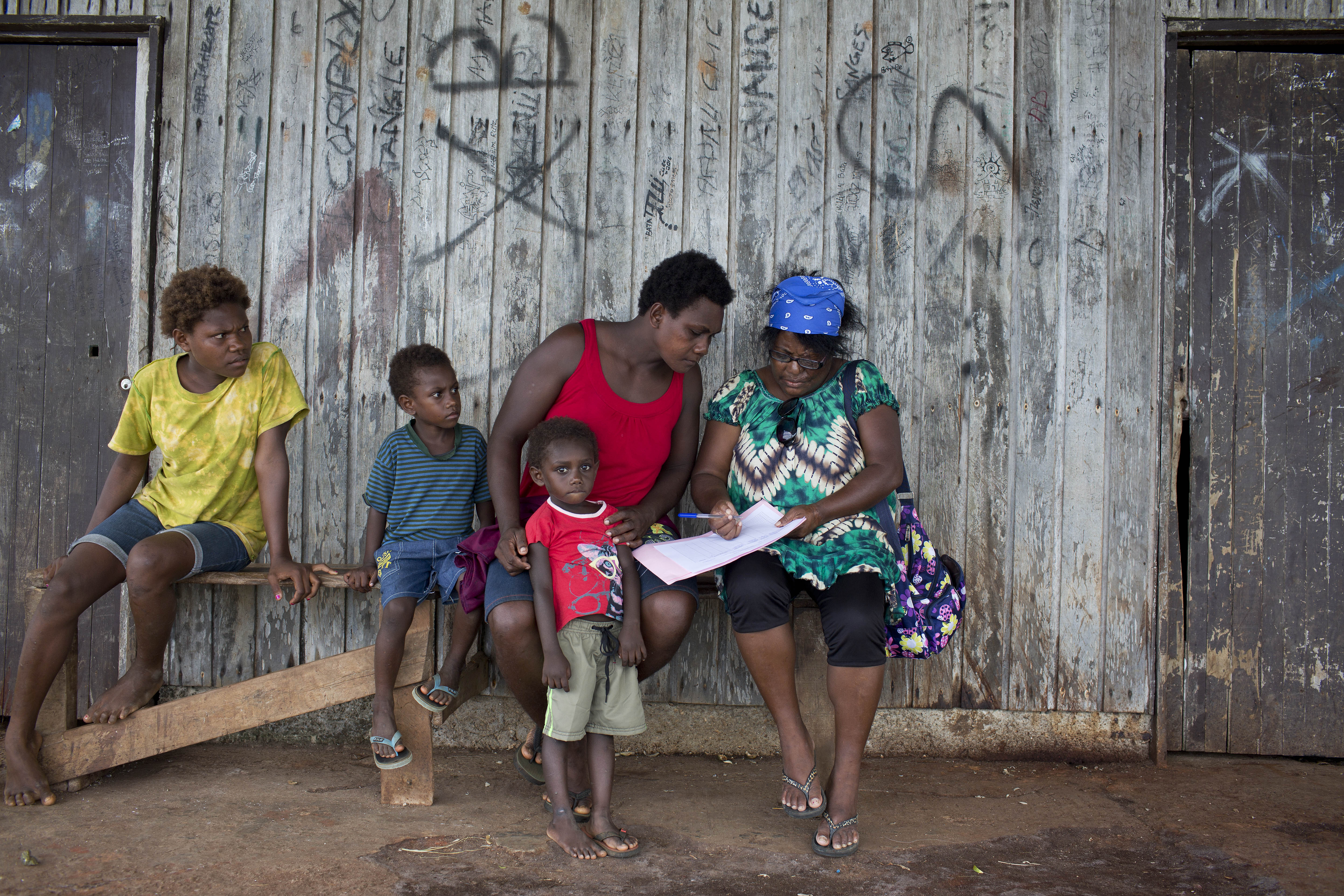 Unicef representative showing information about the vaccination program to a mother with 3 kids