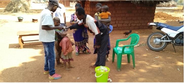 Healthcare workers administer oral polio vaccines to children in a village, as part of a broader campaign to eradicate polio.