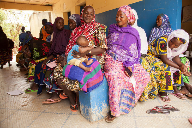 Un groupe de femmes et d'enfants nigériens sont assis et attendent dans un centre de vaccination