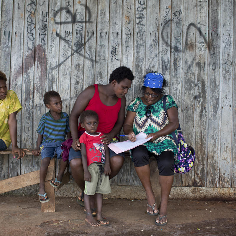 Unicef representative showing information about the vaccination program to a mother with 3 kids
