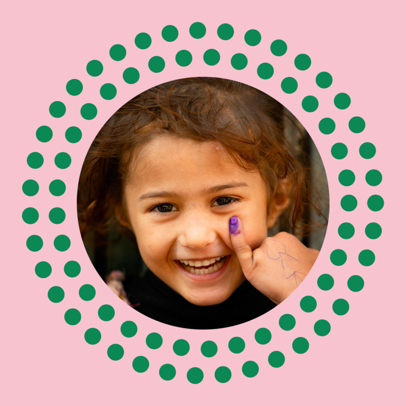 Little girl smilling at the camera and showing her marked pinky