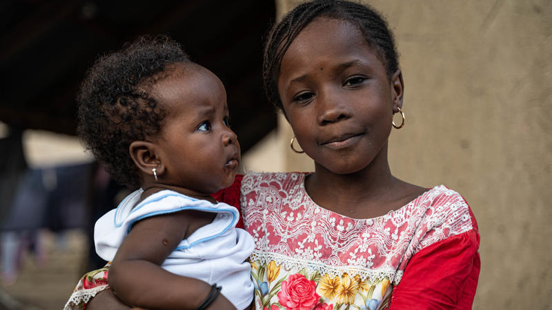 Little girl holding her baby sister and smiling