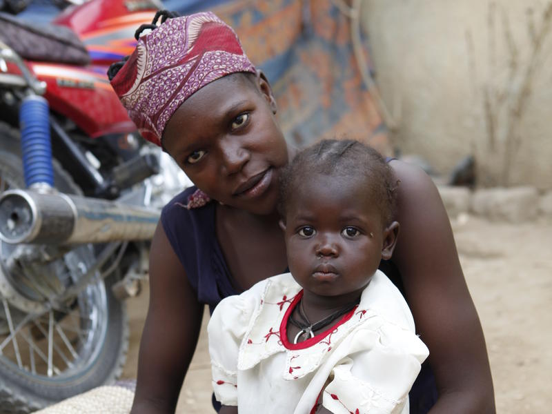 A mother holding her baby sitting on the floor looking at the picture