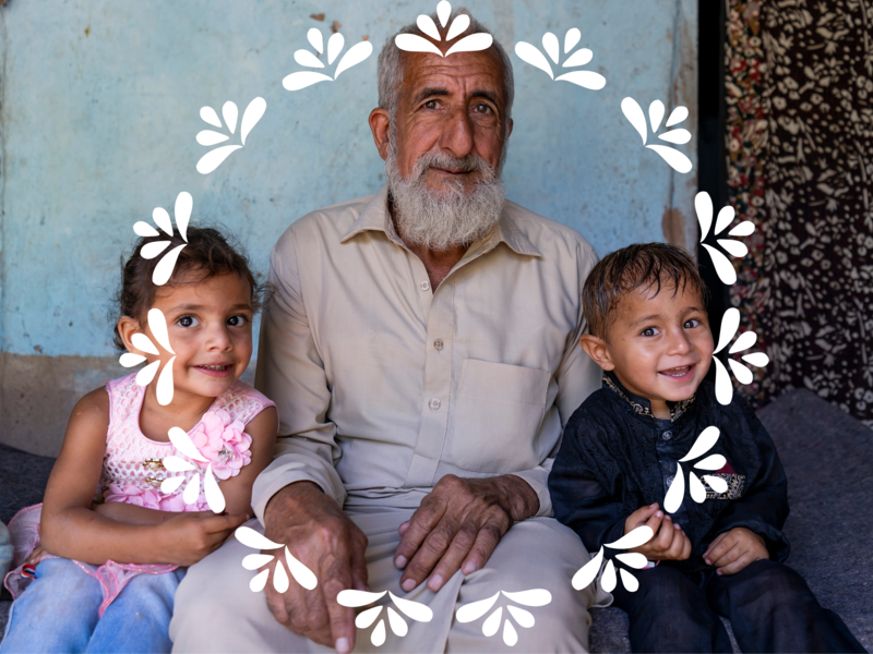 A grandparent and his two grandsons sitting looking at the camera, the children are smilling