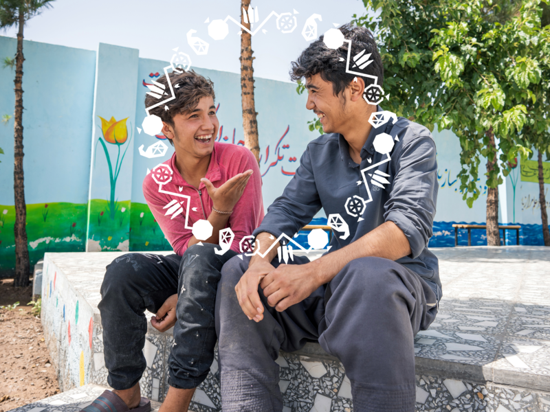 Two teenagers sitting and laughing at each other