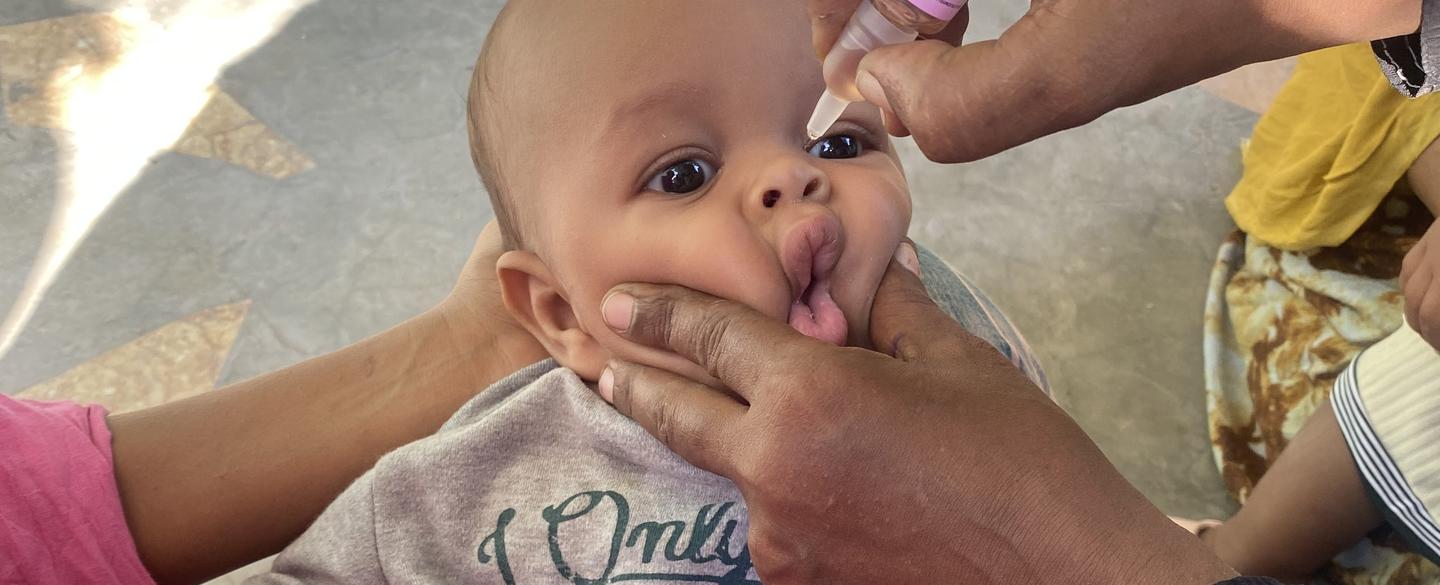 A health worker administers an oral polio vaccine to an infant, ensuring protection against disease